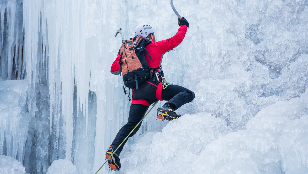 a man ice climbing on a frozen waterfall